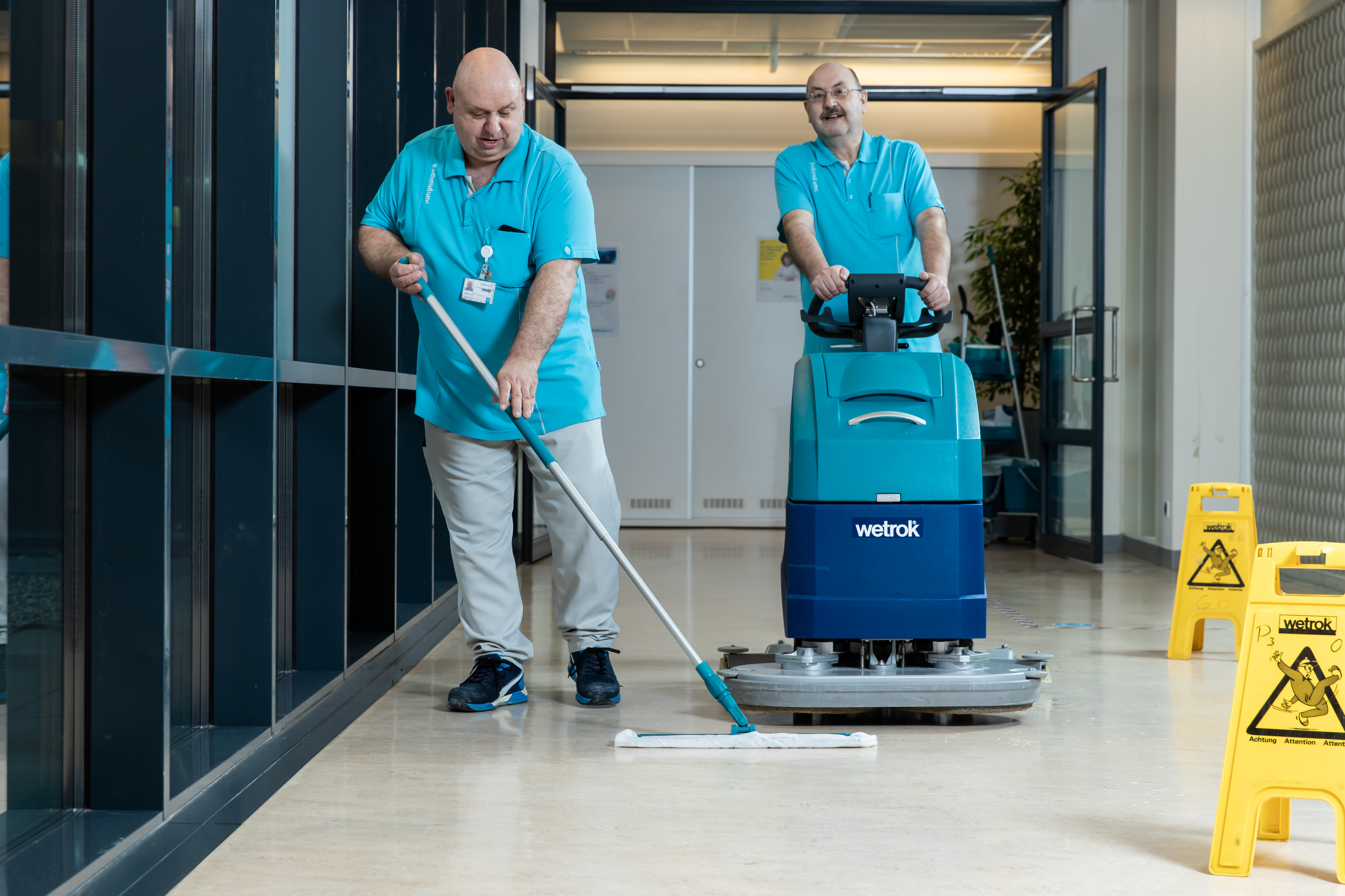 Drie mensen in overleg bij schoonmaakmachine